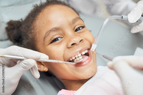 Cute african girl during dental treatment at modern clinic