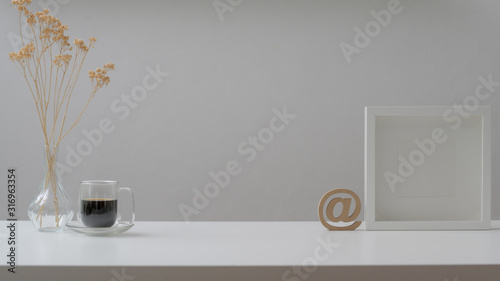 Cropped shot of workspace with mock up frames, coffee cup and decorations on white wooden table © bongkarn