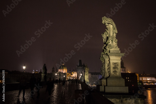 Old town bridge tower of Charles Bridge  Karluv Most   or staromestska mostecka vez in Prague  Czech Republic  at night  with the shapes of tourists walking on it