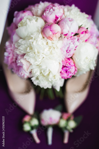 Pair of elegant and stylish bridal shoes with a bouquet with roses and other flowers