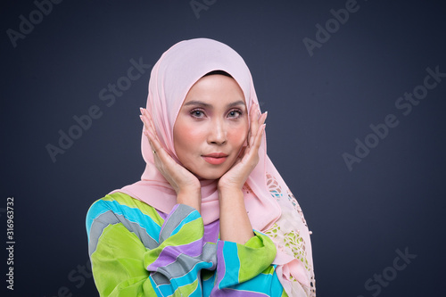 Headshot portrait of a beautiful female Muslim model wearing pastel kaftan with hijab  a modern urban lifestyle apparel for Muslim women isolated on grey background. Beauty and hijab fashion concept.