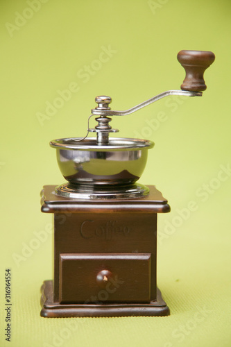 Vintage wooden manual coffee grinder. Close-up isolated on green background