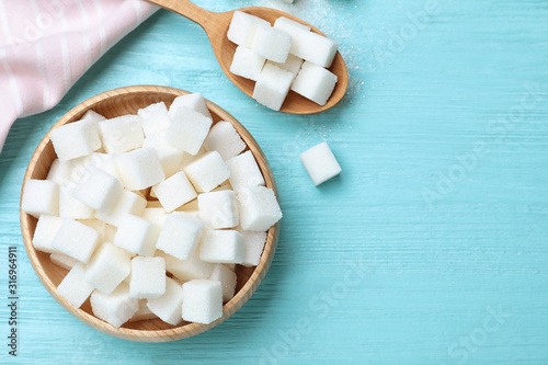 Refined sugar cubes on blue wooden table, flat lay. Space for text photo