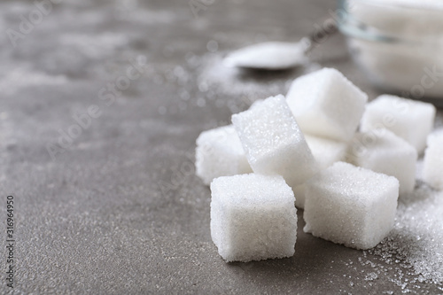 Refined sugar cubes on grey table, closeup. Space for text
