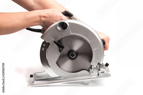 Electric circular saw holding by mans hands .Circular saw is designed for cutting wood and plastic. Object is isolated on white background - Image