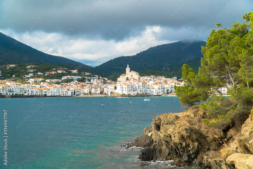 Cadaqués, Catalonia / Spain - November 30th, 2019: Skyline of the old village with an old mediterranean fishing boat