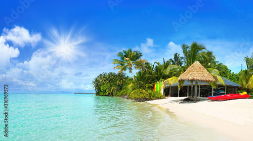 Fototapeta Naklejka Na Ścianę i Meble -  Beautiful beach with white sand, turquoise ocean and blue sky with clouds on Sunny day. Summer tropical landscape with green palm trees and Straw umbrellas.
