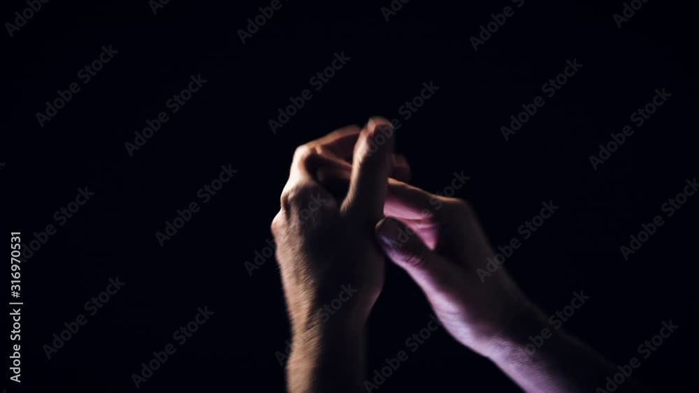 Male hands clapping against a black background.