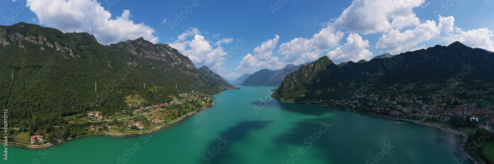 Obraz premium Panoramic view of the mountains and Lake Idro. Reflection in the water of the mountains, trees, blue sky. Aerial view, drone photo