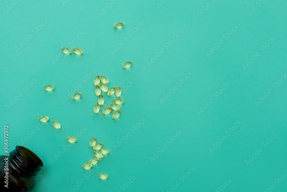 Fototapeta premium Vitamin D bottle with spilled contents on turquoise