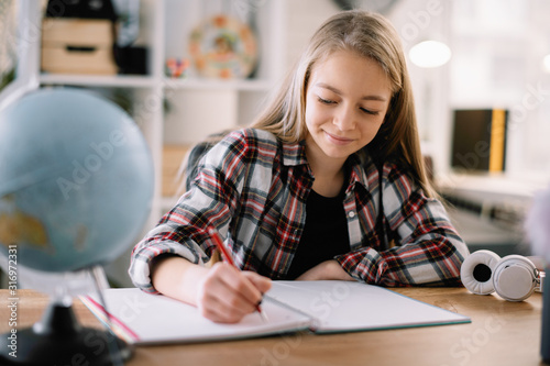 Young girl doing homework. Beautiful little girl at home learning  photo
