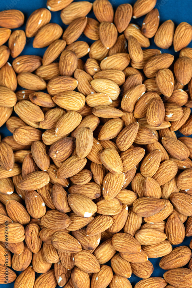Almond seeds texture top view on blue color background, empty space for text, organic healthy food concept Almond seeds texture top view on blue color background, empty space for text, organic healthy food concept