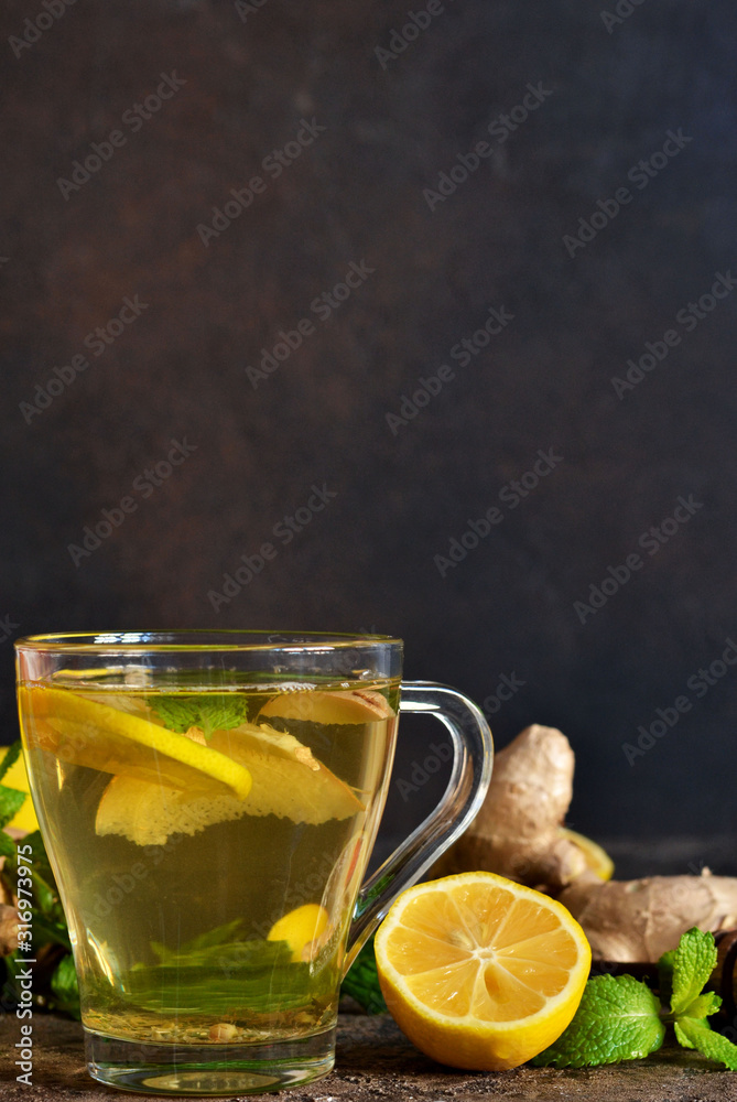 Hot tea with ginger, mint and lemon on a brown concrete background. Horizontal focus.