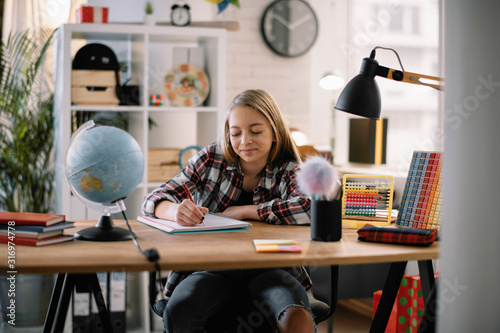 Fotografie Beautiful girl learning at home. Schoolgirl doing homework.
