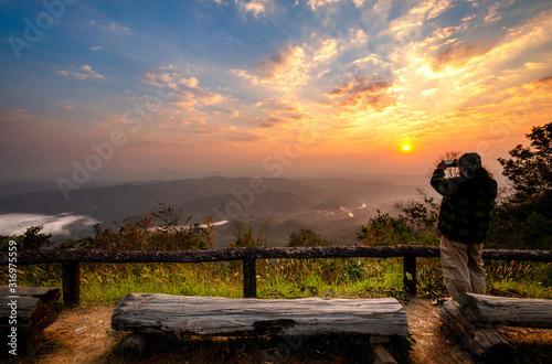 Tourists standing on the edge of the cliffs taking pictures of the sunrise at Doi Samer Dao. See the mountains, the sea of mist and the sunrise in the morning.