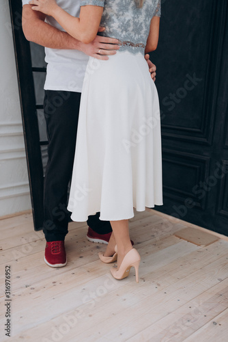 a man in a white t-shirt hugs a girl in a white skirt and shoes