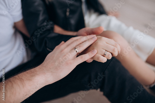 a man and a woman with wedding rings hold each other's hands