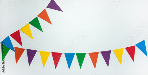 The concept of the birthday in the style of minimalism. Two garlands of multi-colored triangle paper flags on a white background. Free space.