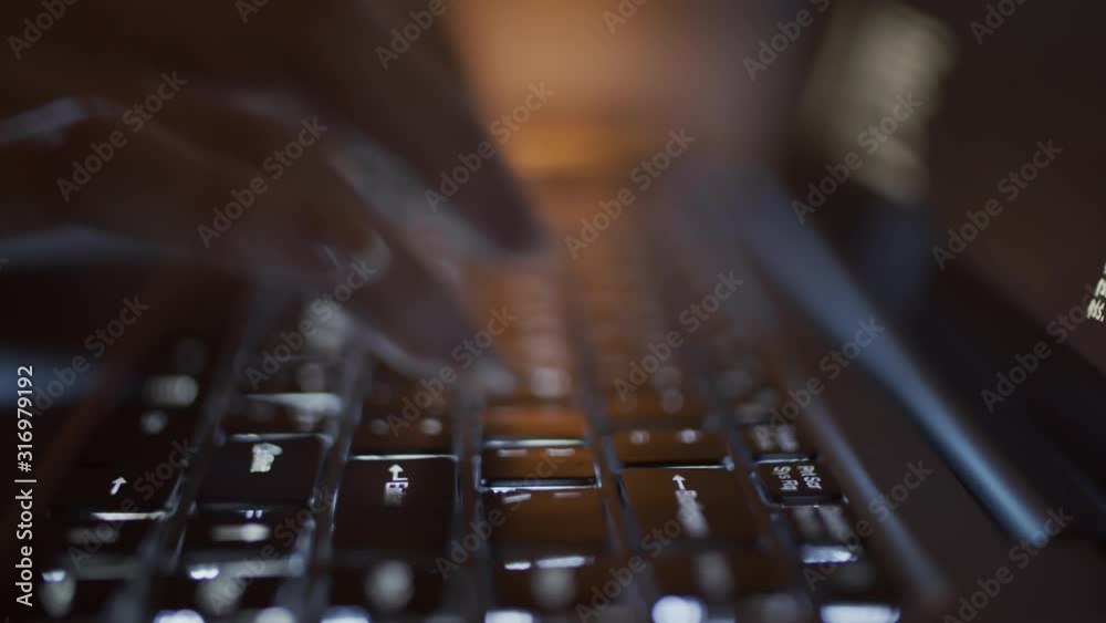 Close-up backlit shot of laptop, hands and fingers of unrecognizable woman typing on keyboard keys in darkness late at night, and lines of symbols moving on black screen