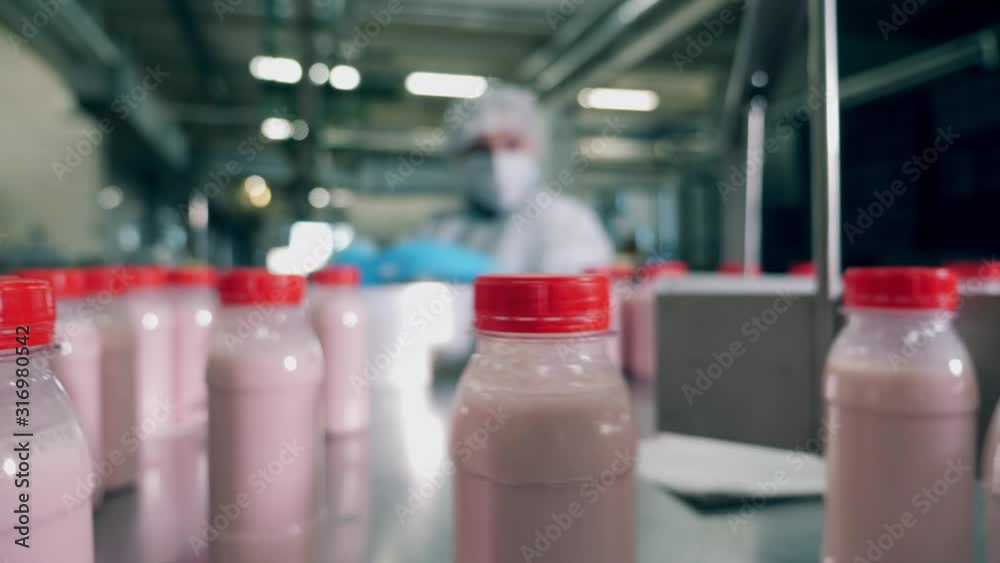 A factory worker picks bottles, moving on a line.