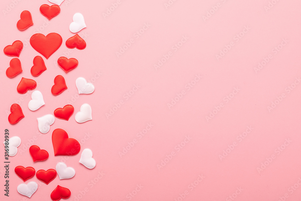 Red and white hearts symbol of love scattered on pink background. Valentine's day concept. Horizontal frame copy space.
