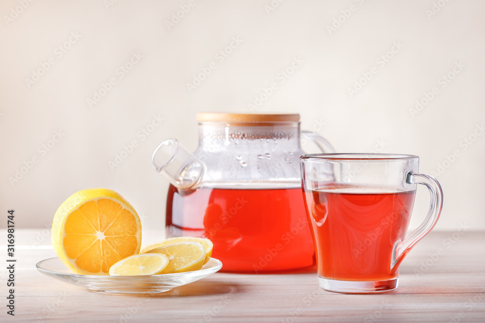 Cup and teapot with tea, lemon on table. Fruit tea with slice of citrus. Cup and teapot with tea, lemon on table. Fruit tea with slice of citrus.