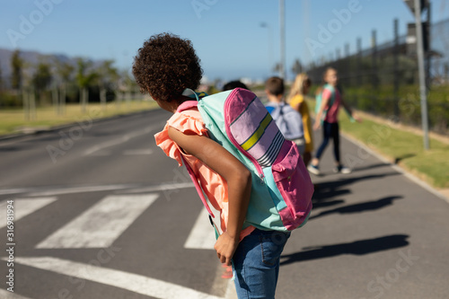 Schoolchildren looking for traffic while waiting to cross the road