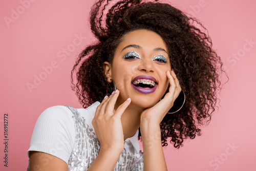 Slika na platnu excited african american girl with dental braces, with silver glitter eyeshadows