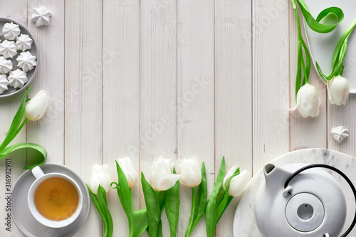 Mothers day, St. Valentine, international women day 8 or March, birthday or some special occasion. Spring decorations on white wooden boards, copy-space. Tulips, flowers, tea cup, pot, marshmallows.. photo