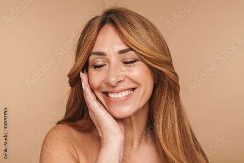 Portrait of shirtless adult woman touching her face and smiling