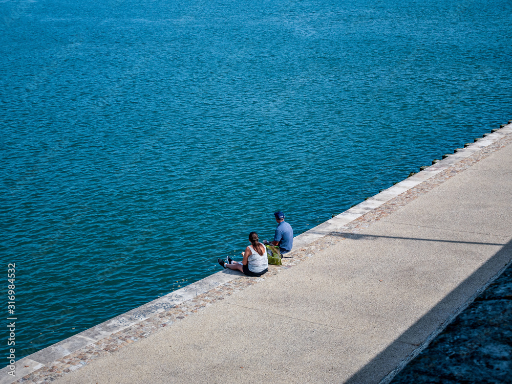 man and woman sitting near the river rhone