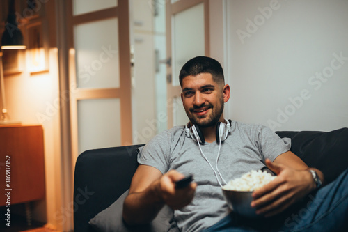 man at home watching tv and eating popcorn