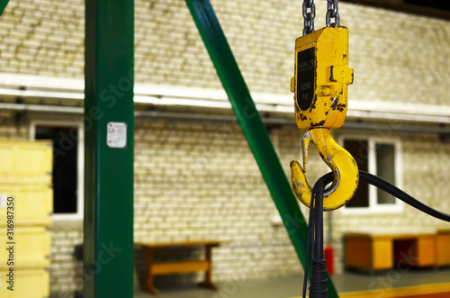 Crane hook of the overhead crane in the workshop of an industrial plant. Push remote control switch for lifting crane in the factory