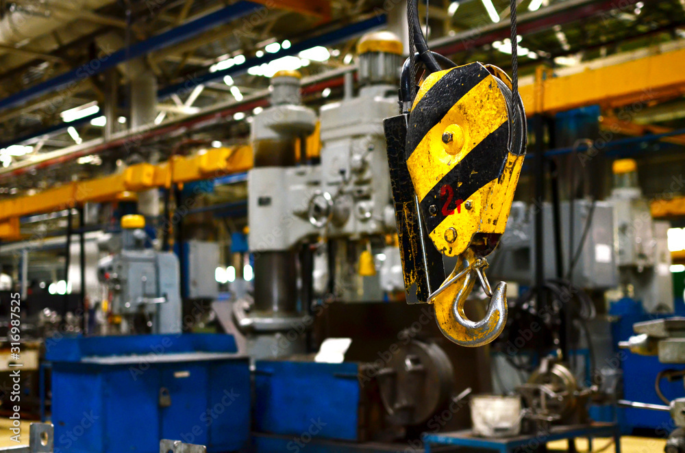 Crane hook of the overhead crane in the workshop of an industrial plant.  Push remote control switch for lifting crane in the factory