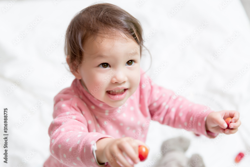 Enfant mix 2 ans franco chinois tendant des cerises Enfant mix 2 ans franco chinois tendant des cerises