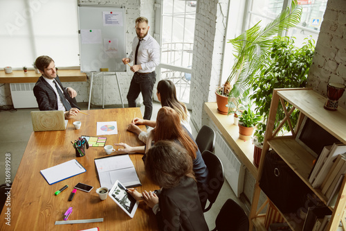 Top view. Group of young business professionals having a meeting. Diverse group of coworkers discussing new decisions, future plans, results, strategy. Creativity, workplace, business, finance.