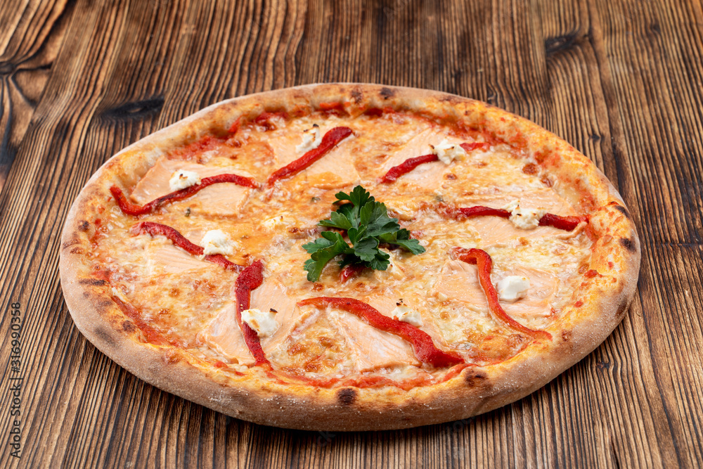 Baked seafood pizza with melted cheese and ketchup on wooden background