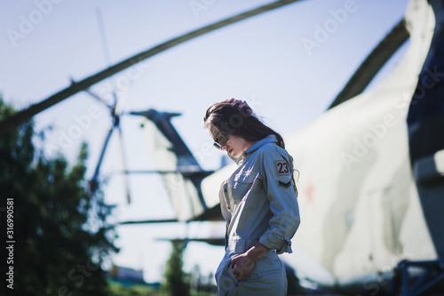 beautiful woman in a military uniform and sunglasses on the background of an airplane