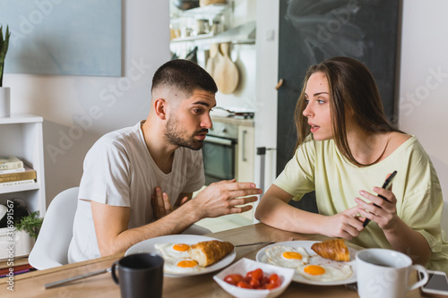 young couple arguing in kitchen during breakfast. relationship problems