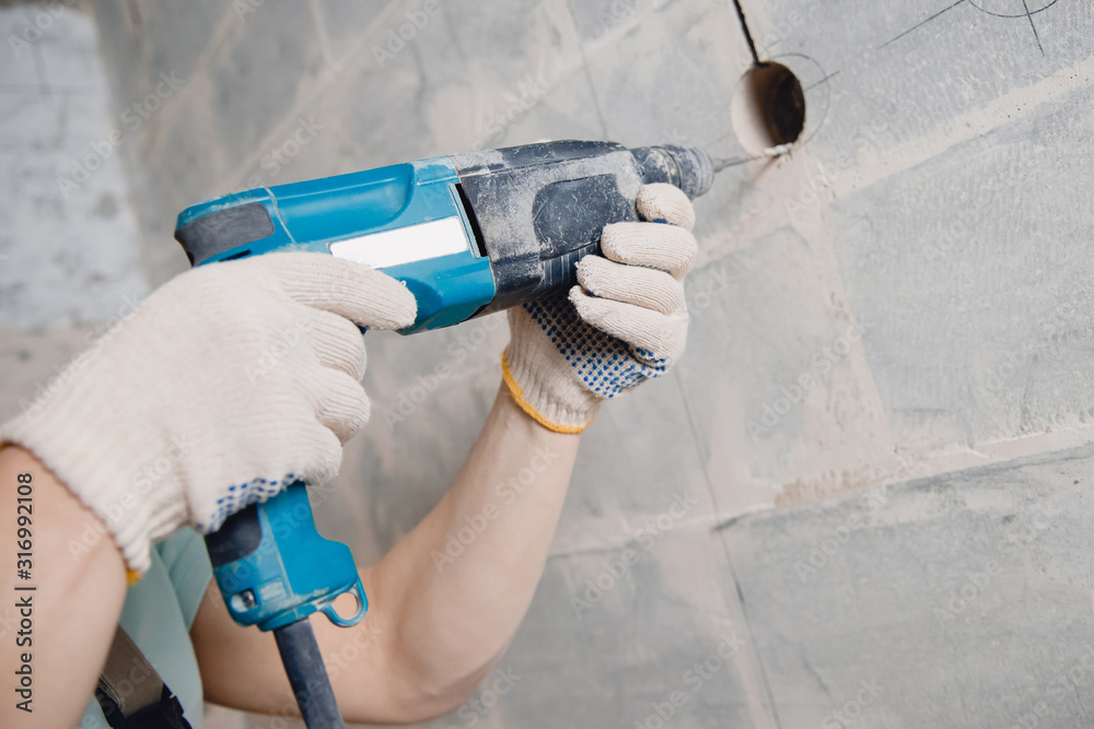 Builder man with pneumatic hammer drill perforator with diamond crown  making hole in wall for electric cable, socket, switch Stock-Foto | Adobe  Stock