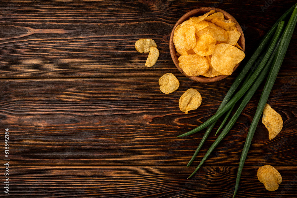 Fototapeta premium Crisps and green onion on dark wooden background.