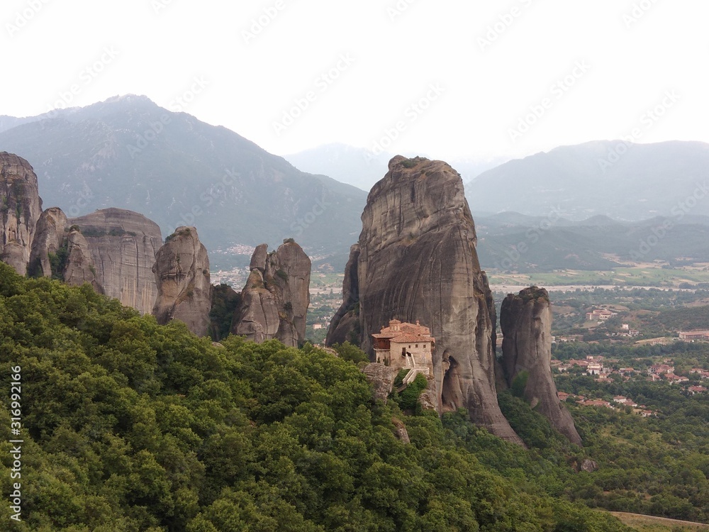 Monastery on a mountain peak in Meteora Greece surrounded by limestone peaks and background of grey mountains