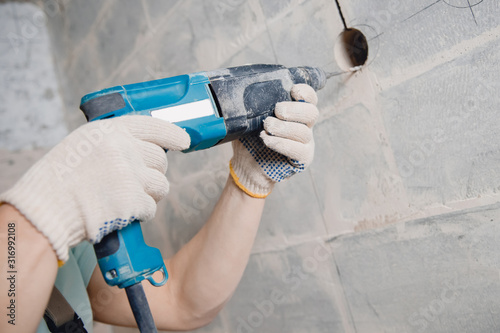 Fotografía Builder man with pneumatic hammer drill perforator with diamond crown making hol