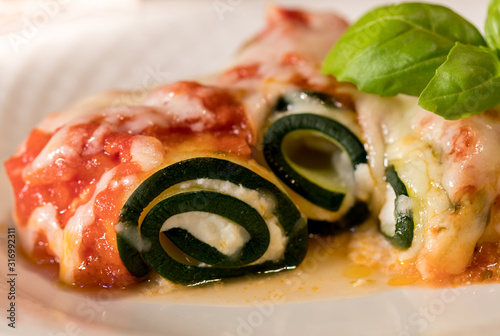 Delicious Zucchini Rollups filled with ricotta cheese and topped with fresh tomato marina, mozzeralla and spring of basil photo