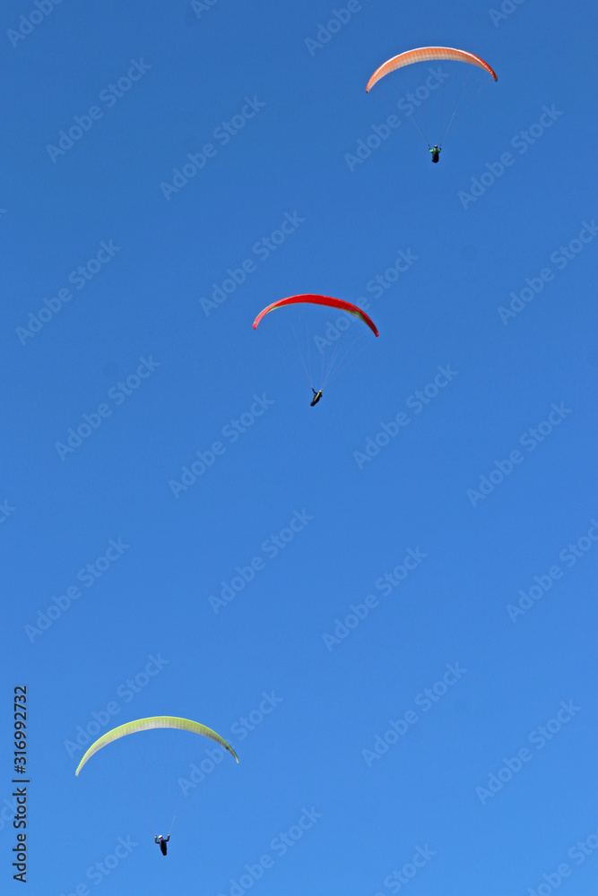 Paragliders flying wings in a blue sky Paragliders flying wings in a blue sky