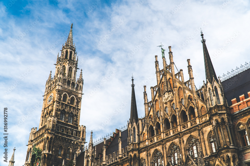 Fototapeta premium The New Town Hall, Neues Rathaus on Marienplatz main square, city government building with a tower clock. Gothic style. Photographed from below. Wide shot.