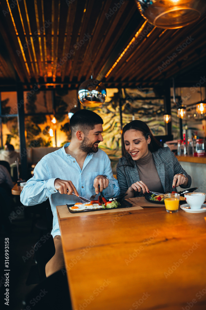 happy young couple having lunch in restaurant