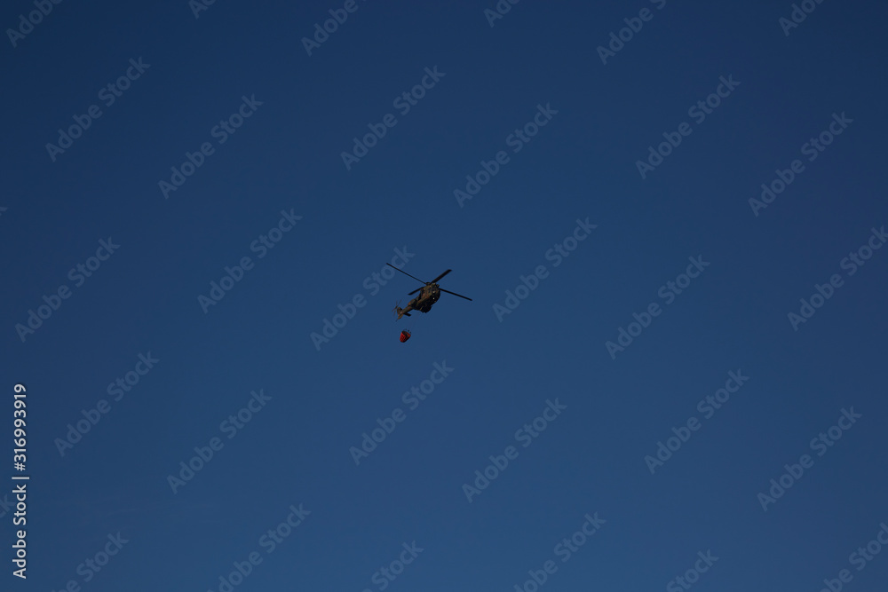 Helicopter / chopper flies to drop water on wildfire Helicopter / chopper flies to drop water on wildfire
