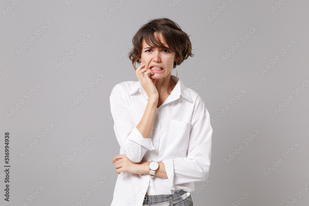Displeased nervous young business woman in white shirt posing isolated on grey background studio portrait. Achievement career wealth business concept. Mock up copy space. Put hand prop up on chin. Displeased nervous young business woman in white shirt posing isolated on grey background studio portrait. Achievement career wealth business concept. Mock up copy space. Put hand prop up on chin.