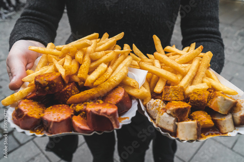 Canvastavla Woman hands holding traditional red and white curry wurst and french fries at Vi